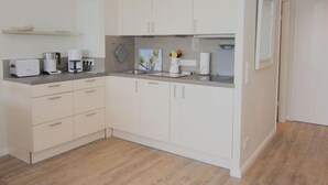 Una cucina moderna con mobili bianchi, un piano di lavoro con elettrodomestici e un pavimento in legno.