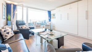 Een moderne woonkamer met een glazen salontafel, een leren bank en uitzicht op de stad door grote ramen.
