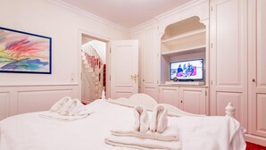 Una camera d'albergo con un letto grande, una televisione e una scala che conduce a un'altra stanza.