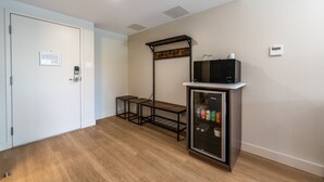 A room with a white door, a small table, a microwave on a cabinet, and a thermostat on the wall. - Rooms at Riveredge (Golden)