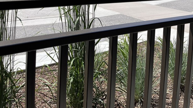 A view from a balcony with a railing, featuring a street with trees and a mountain range in the background. - Rooms at Riveredge (Golden)