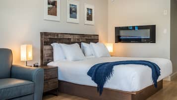 A neatly arranged bedroom with a large bed, a wooden headboard, a TV mounted on the wall, and framed pictures above the bed.