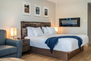Quarto bem arrumado com uma cama grande, cabeceira de madeira, televisão na parede e quadros acima da cama.
