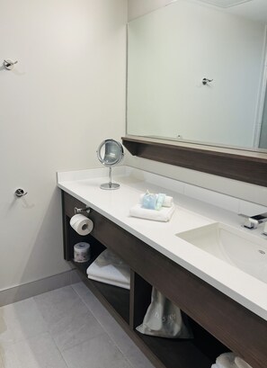 A modern bathroom with a white sink, a round mirror, and a towel rack.