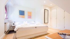 A modern bedroom with a bed, bedside tables, a wardrobe, and artwork on the walls. - Twesk Diker 3, Germany (Sylt-Ost)