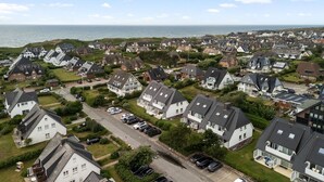 Ein Wohngebiet mit Häusern, einer Straße und einem Gewässer im Hintergrund.