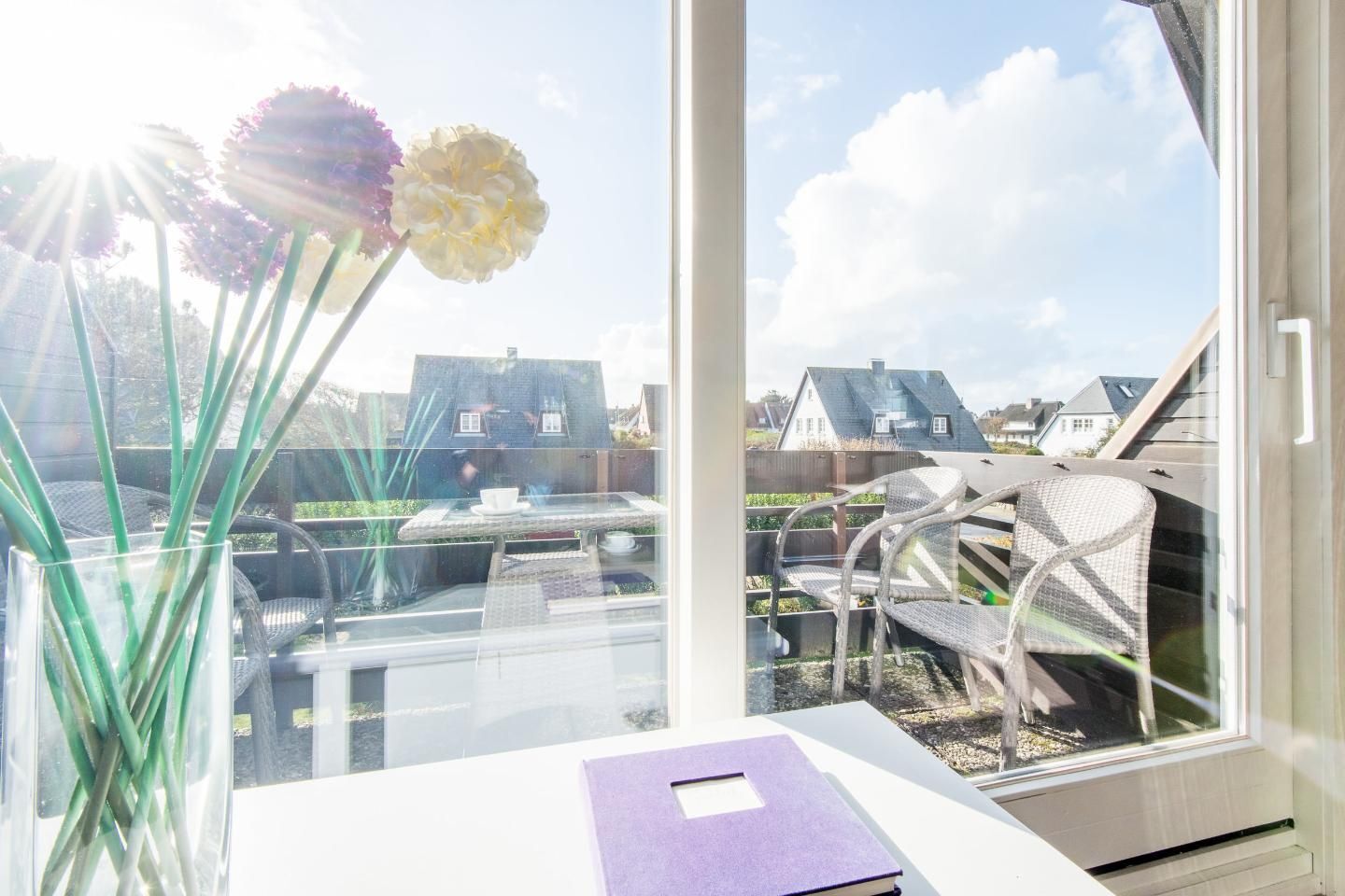 A room with a large window, a white table, and a purple book.