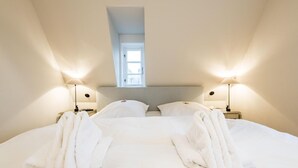 Une chambre d’hôtel avec un grand lit, deux lampes de chevet, une fenêtre et une tête de lit.