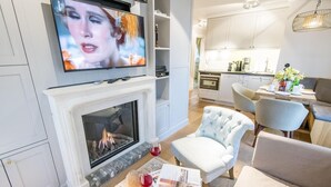 Un salon moderne avec une cheminée, un téléviseur et un coin repas avec une table mise pour deux personnes.