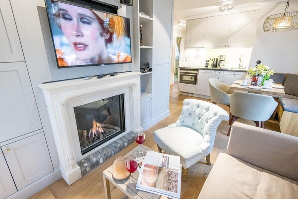 Un salon moderne avec une cheminée, un téléviseur et un coin repas avec une table mise pour deux personnes.