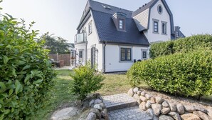 Une maison à deux étages, dotée d’un toit à forte pente, d’un porche à l’avant et d’un chemin de pierre menant à l’entrée.
