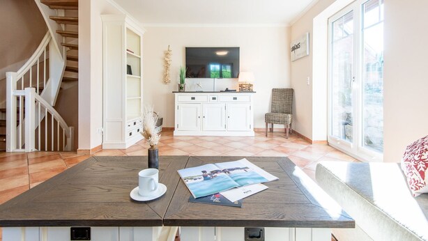 Un salon spacieux avec une table basse en bois, un canapé blanc, un téléviseur et une grande fenêtre.