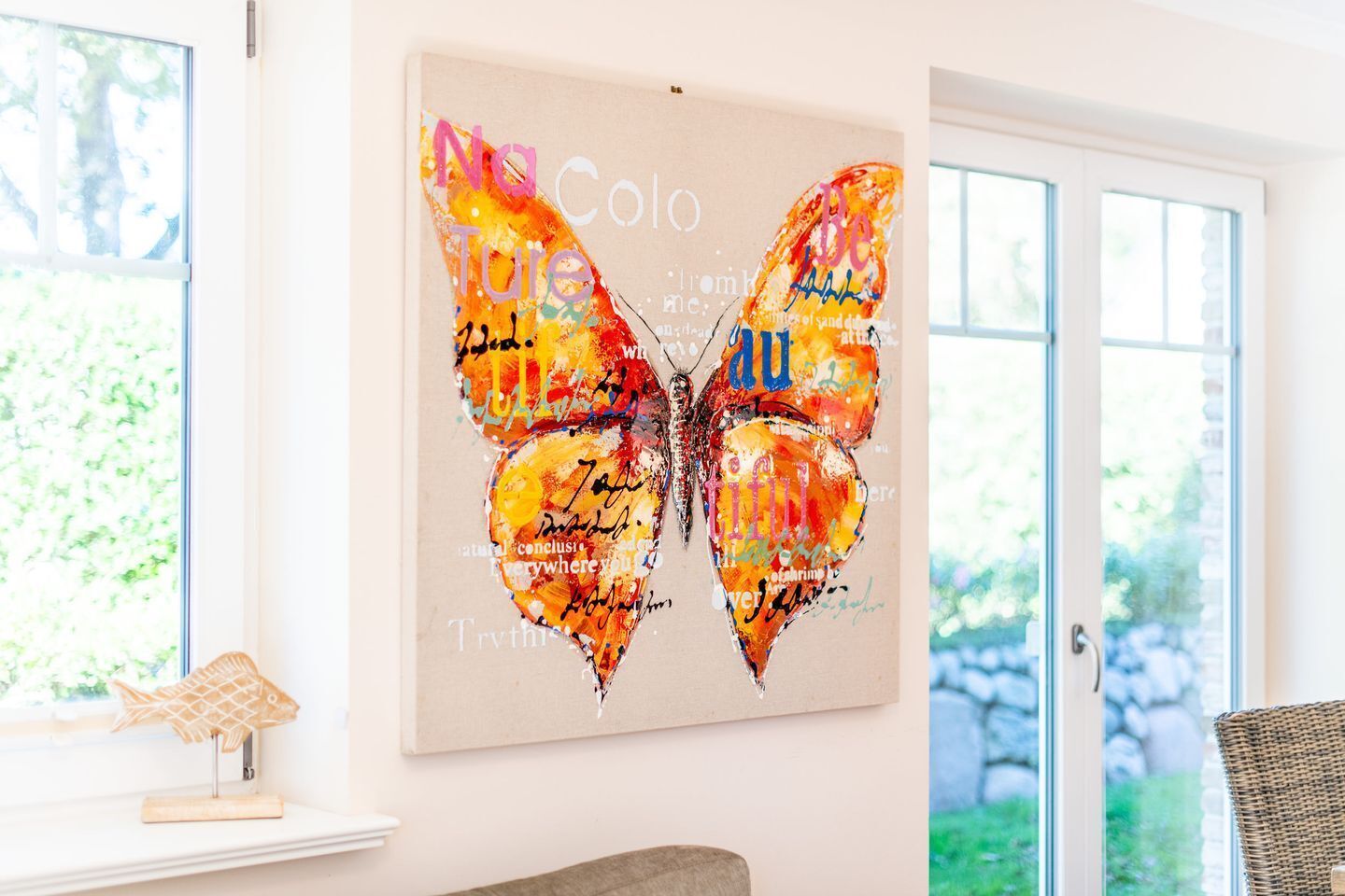 Een vlinderkunstwerk op een muur in een kamer met een raam en een deur.