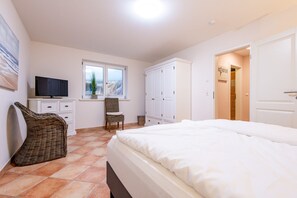 Une chambre à coucher comprenant un lit, une télévision, une chaise, une armoire et une fenêtre donnant sur un beau paysage.