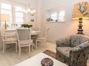 A dining area with a round table and chairs, a sofa, and a lamp.