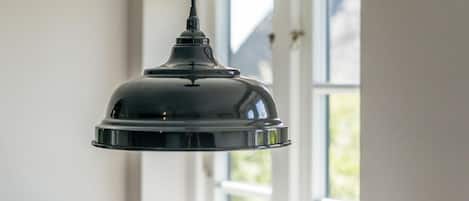A pendant light fixture hanging in a room with a window in the background.