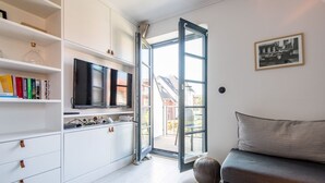 A modern living room with a sofa, a television, and a bookshelf. - Villa Maybach, Whg. 8 - Villa Maybach (Sylt)