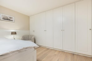 Ein Schlafzimmer mit Bett, Stuhl, Kleiderschrank und Lampe.