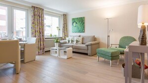Ein modernes Wohnzimmer mit einer Couch, Sesseln, einem Couchtisch und einer Stehlampe.