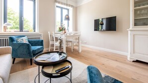 Una sala de estar moderna con un sofá, una mesa de comedor y un televisor montado en la pared.