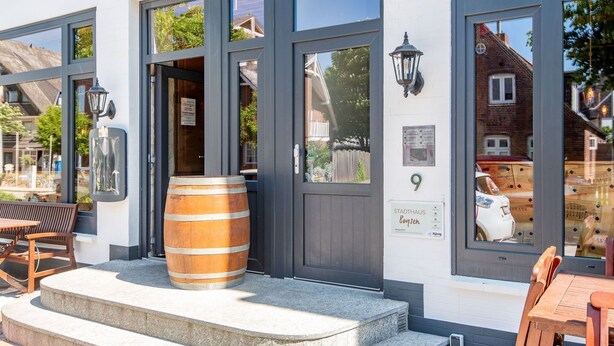 A building with large windows, a wooden barrel, and outdoor seating.