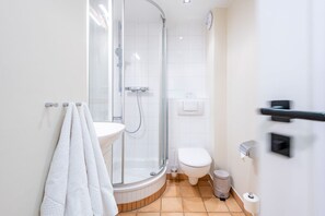 Une salle de bain moderne avec une douche à parois de verre, des toilettes blanches et un lavabo doté d’un porte-serviettes.