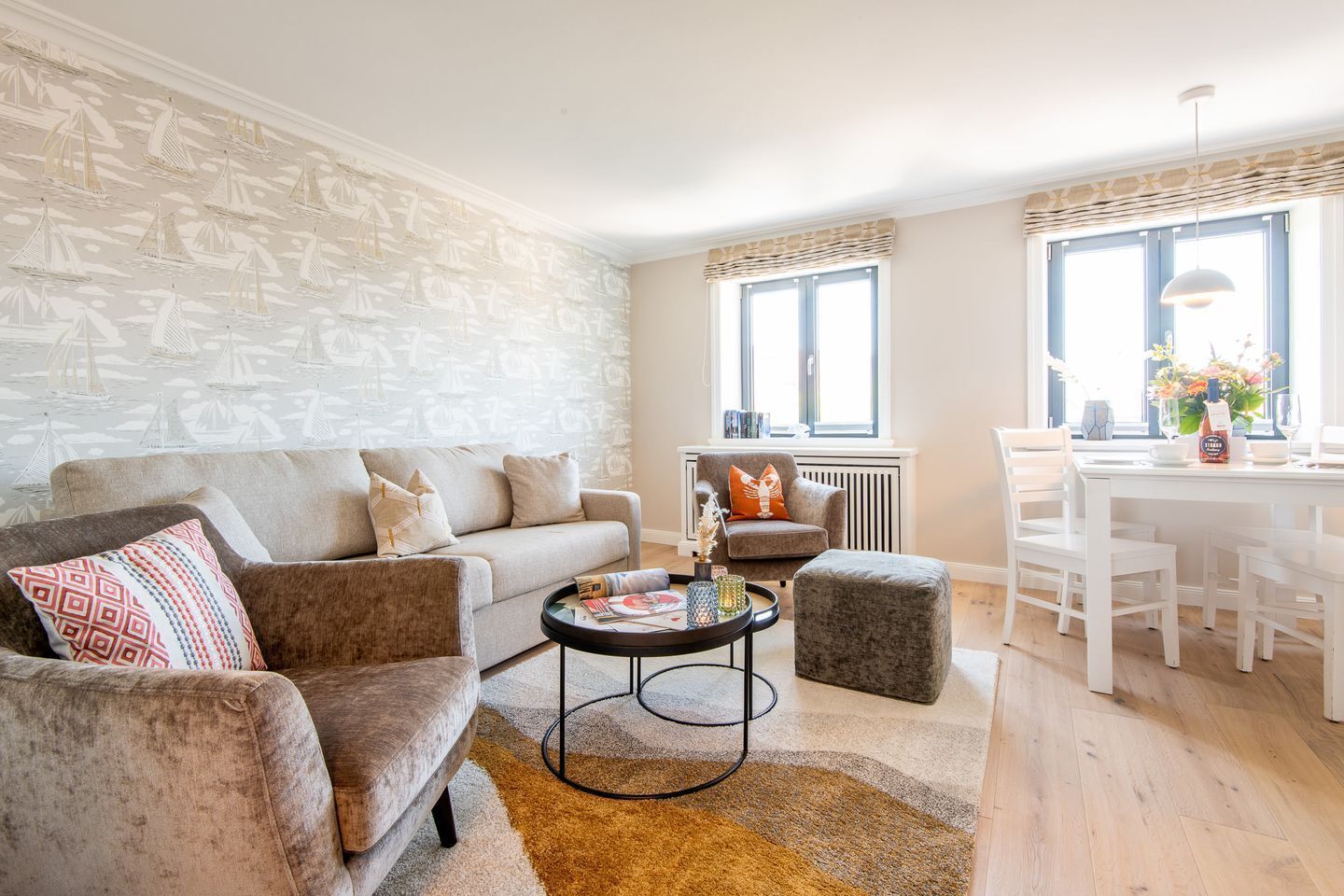A living room with a sofa, armchair, coffee table, and dining area with a white table and chairs.