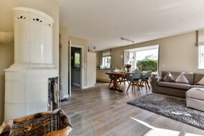 A spacious living area with a fireplace, a dining table with chairs, a sofa, and a large window providing natural light.