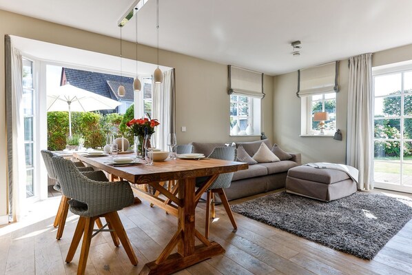 A modern dining area with a wooden table, wicker chairs, and a sofa.