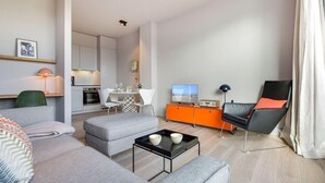 A modern living room with a grey sofa, a black coffee table, and a dining area with a white table and chairs.