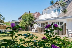 A residential house with a covered patio, a fenced backyard, and a tree. - Modern. Bright. Central. - House Friesische Straße (Sylt)