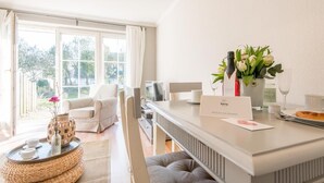 Una habitación de hotel moderna con un ventanal grande, un área de comedor con una mesa dispuesta para dos personas y una zona de estar acogedora con una silla y un sofá.