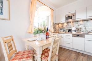 A modern kitchen with white cabinets, a built-in microwave, and a coffee maker.