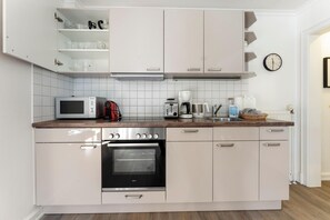 A modern kitchen with a microwave, toaster, coffee maker, and a built-in oven. - Gemütlich. Strandkorb. Ruhig. - Senwai-hüs, Whg. 2 "keitum" - Objekt-id: Hsw/02 - Senwai-hüs (Sylt)