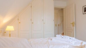 A hotel room with a bed, a lamp, and a wardrobe. - Ruhe. Balkon. Gemütlich. - Senwai-hüs, Whg. 3 "morsum" - Objekt-id: Hsw/03 - Senwai-hüs (Sylt)