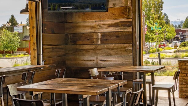 Un interior rústico con un gran muro de madera, un televisor montado y una zona de bar con taburetes.