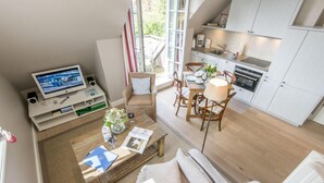 A modern living space with a TV, seating area, dining table, and kitchen. - Exquisit. Wellness. Modern. - Objekt-id: Hm/05 - Haus Magnus (Sylt)