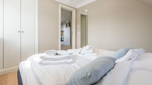 A hotel room with a large bed, a wardrobe, and a view into the kitchen. - Exquisit. Wellness. Modern. - Objekt-id: Hm/05 - Haus Magnus (Sylt)