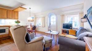 Una sala de estar acogedora con un sofá, sillones, una mesa de comedor y un televisor.