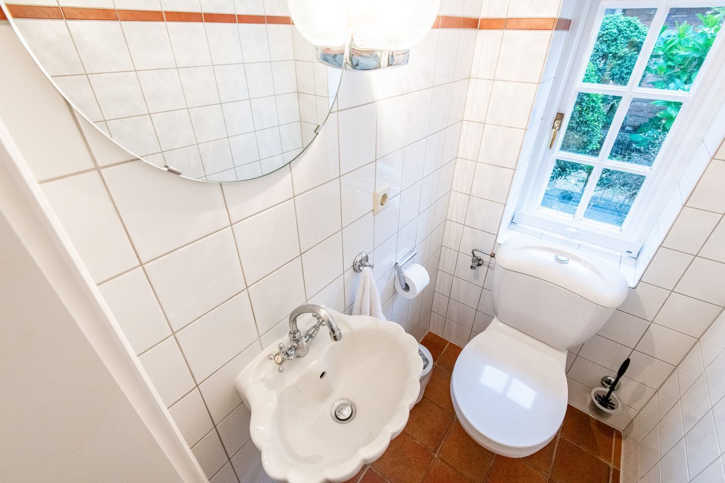 Une salle de bain avec un lavabo, des toilettes et une fenêtre.