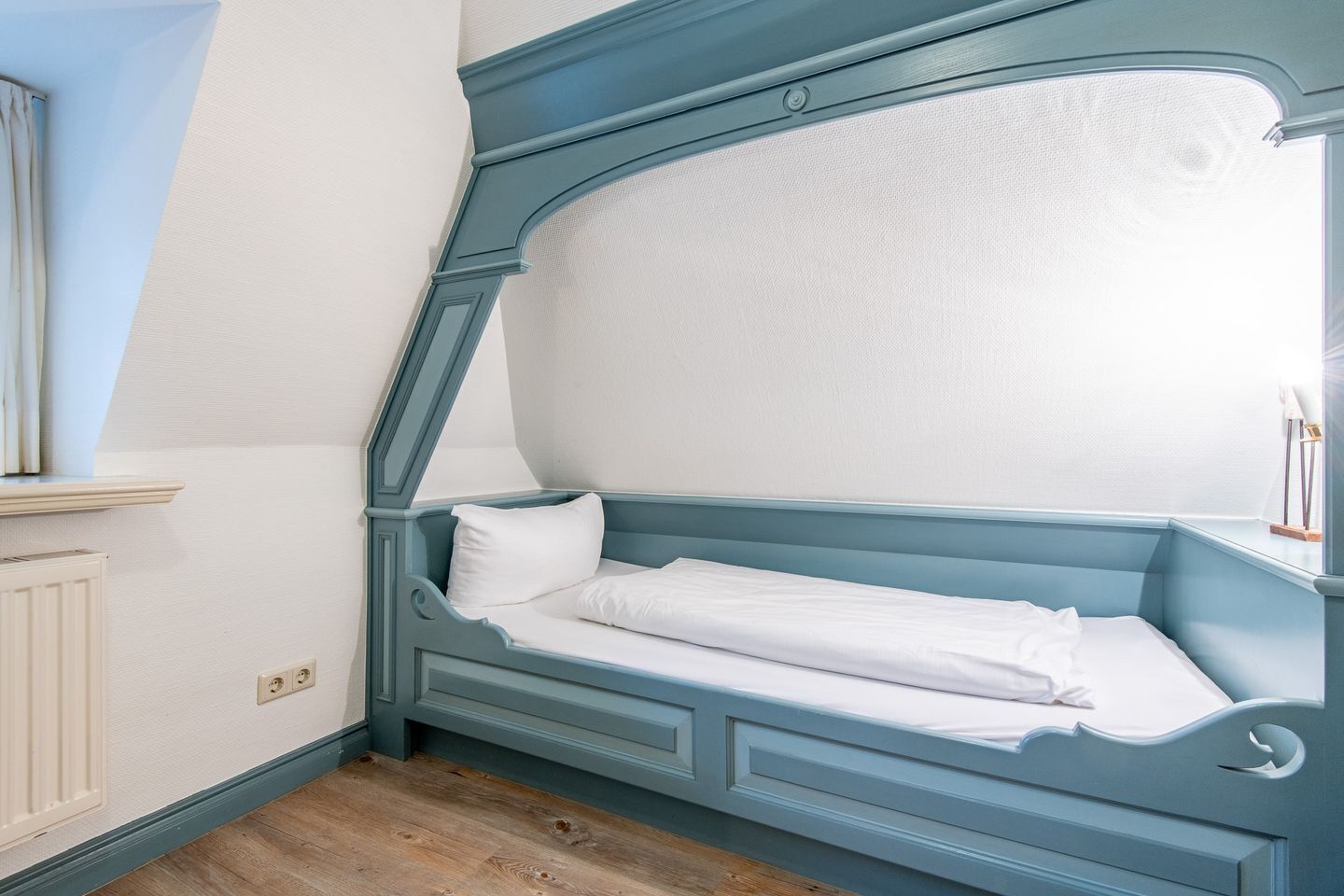 Un dormitorio con una cama individual, una ventana y un radiador.