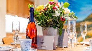 Un tavolo apparecchiato con una bottiglia di vino, un'esposizione floreale e un biglietto di benvenuto per KÖNIG APARTMENT.