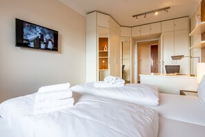 Ein Hotelzimmer mit einem Bett, einem an der Wand montierten Fernseher und einem Schrank mit Spiegel.