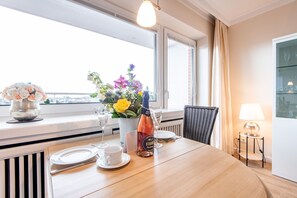 Ein Hotelzimmer mit einem Holztisch für zwei Personen, einer Blumenvase, einer Champagnerflasche und einer Lampe auf einem Beistelltisch.