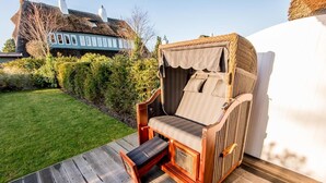 A wicker chair with a cushioned seat and backrest, placed on a wooden deck.