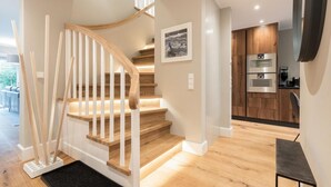 A modern kitchen with built-in appliances and a wooden staircase.