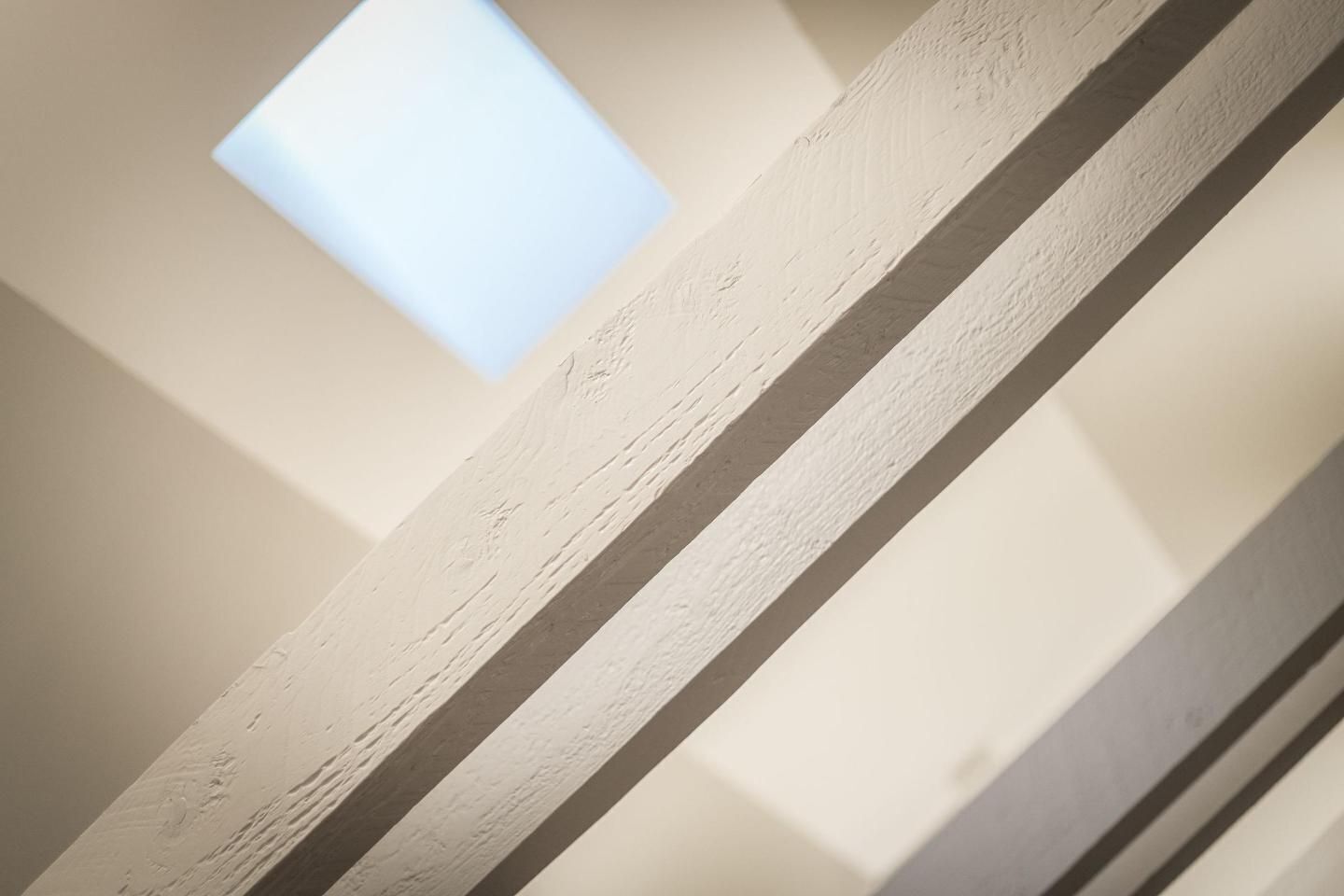 Una viga de madera blanca con una ventana encima.