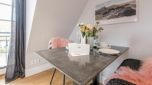 Uma sala de jantar moderna com uma mesa posta para dois, um vaso com flores e um quadro na parede.