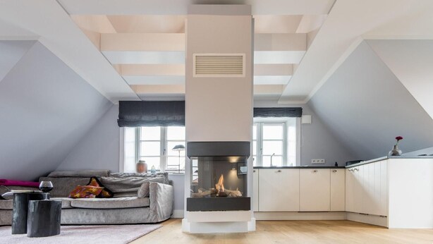 Um loft moderno com lareira, sofá e cozinha.