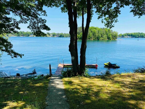 Une vue sur le lac, avec un quai, un jet ski et un bateau à rames.